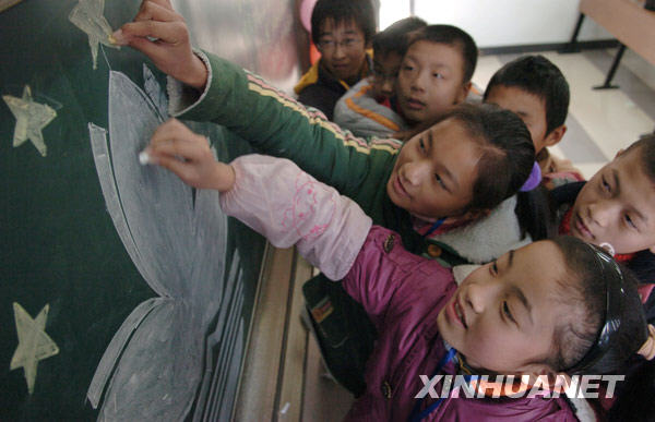 12月20日，两个农民工孩子用粉笔在黑板上描绘澳门特别行政区区旗。